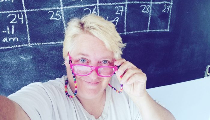 high-angle-portrait-smiling-teacher-wearing-eyeglasses-against-blackboard